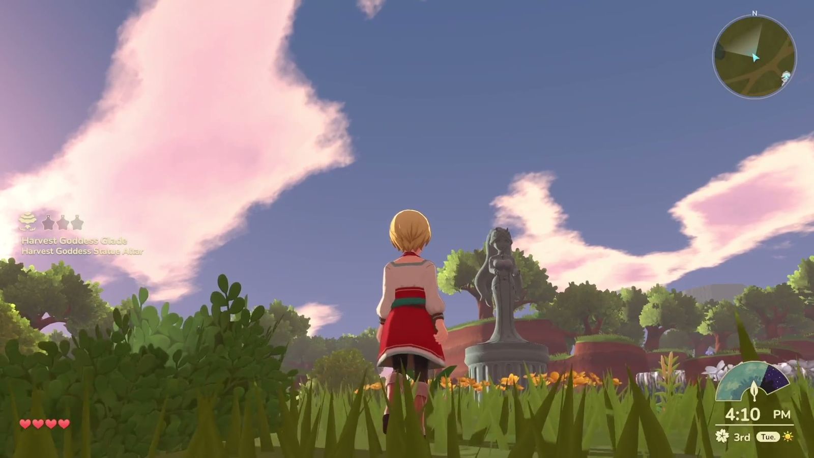 Official trailer frame: the player standing before a statue on open ground